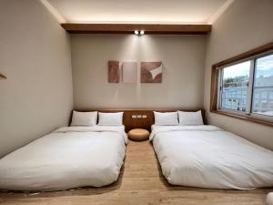 台南河趣泊旅 River Chill Inn的配有白色床单的客房内的两张床