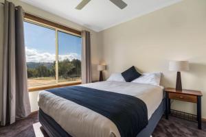 BiggaReflections Grabine Lakeside - Holiday Park的一间卧室设有一张大床和一个大窗户