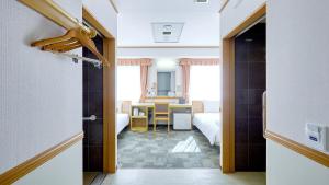 久留米市Toyoko Inn Nishitetsu Kurume eki Higashi guchi的走廊上设有卧室和桌子的房间