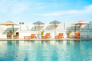 Ban Bang Phli Yai蓝天机场酒店的一组椅子和遮阳伞,位于游泳池旁