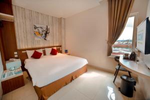 沙马林达Zoom Hotel Mulawarman的配有一张床、一张书桌和一扇窗户的酒店客房