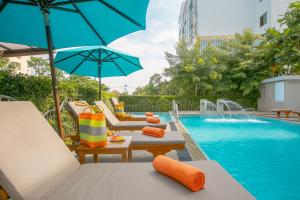 普吉镇普吉岛苏伦酒店的游泳池旁设有椅子和遮阳伞