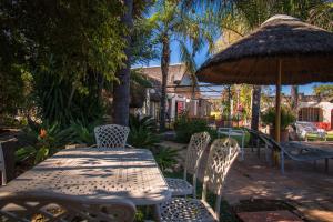 OtaviGabus Safari Lodge的庭院里配有桌椅和遮阳伞