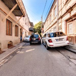 第比利斯Hostel Pirosmani的两辆汽车停在建筑物旁边的街道上