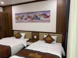 下龙湾Anika Hotel的酒店客房设有两张床,墙上挂有绘画作品