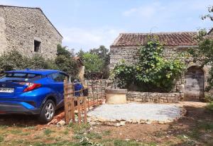 Payré-sur-VendéeLe Fournil de Payré的停在石头建筑前面的蓝色汽车