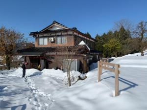 长滨市余呉の里山-ランプの宿-さくら的站在房子前的雪中的一个男人