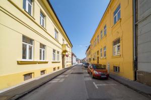 科希策GUDU apartments的一条黄色建筑的小巷和一条停在街上的汽车