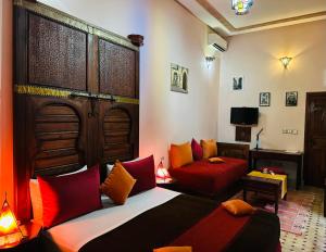 非斯里亚德阿拉姆酒店的一间卧室配有两张带红色和橙色枕头的床
