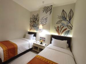 巨港Kesuma Front One Boutique Palembang的酒店客房设有两张床,墙上挂有绘画作品
