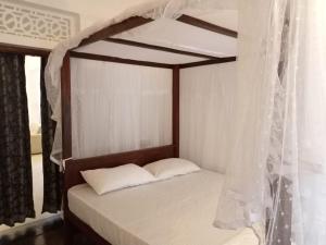 韦利格默Shine Breeze villa的卧室配有带白色窗帘的天蓬床