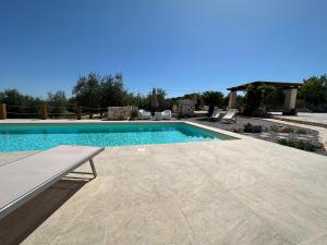 奥斯图尼Trulli Santa Maria Odegitria Relais的庭院内带长凳的游泳池