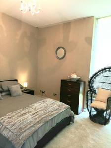 沃特福德Beautiful 2-Bed Apartment near Waterford City的一间卧室配有一张床、一把椅子和闹钟