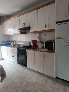 希韦罗Albergue Camiño Real的厨房配有白色橱柜和黑色冰箱。
