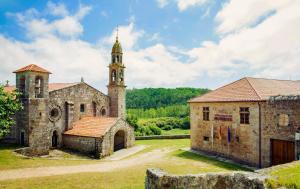 穆希亚Monasterio y Pensión de Moraime的一座古老的石头建筑,有塔楼和教堂