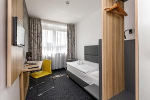 俄斯特拉发协和俱乐部酒店的一间卧室配有一张床、一张桌子和一张黄椅