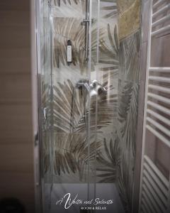 托尔基亚罗洛AvVolta nel Salento - Room & Relax的玻璃门和植物壁画的淋浴