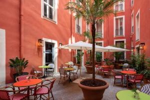 罗马UNAHOTELS Trastevere Roma的一个带桌椅的户外庭院和棕榈树