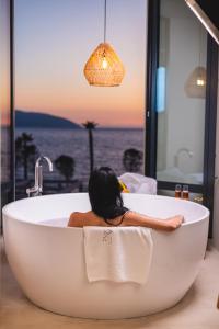 伏罗拉Azar Luxury Suites的坐在浴缸中的女士,享有海景