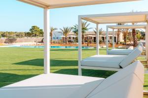坎波斯Cantó de Marina- Adults Only的游泳池旁草坪上的两张白色床