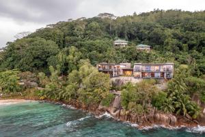 马埃岛贝拉扎尔区Mango House Seychelles, LXR Hotels & Resorts的大海旁山丘上房屋的空中景观