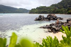 马埃岛贝拉扎尔区Mango House Seychelles, LXR Hotels & Resorts的两个人坐在海滩上的岩石上