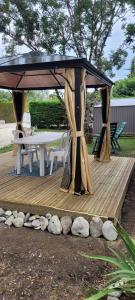 奥雷龙圣皮耶尔La cabane Oléronnaise的一个带桌子和一些岩石的木制凉亭