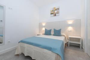 马拉加Victoria's Apartamentos的白色卧室配有一张带蓝色枕头的大床
