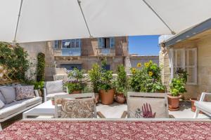瓦莱塔Stunning Valletta Palazzino的庭院配有白色遮阳伞、椅子和植物
