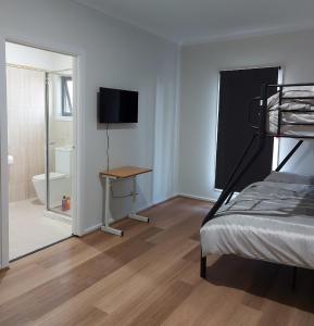 墨尔本Maruve Guesthouse 12 min from Melb airport的一间卧室配有一张床、一张书桌和一台电视