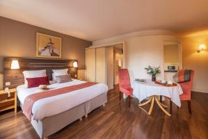 吕克瑟伊莱班HOTEL CERISE - LES SOURCES Luxeuil-les-Bains的酒店客房带一张床、一张桌子和椅子