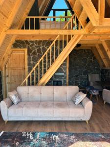 里泽Oruba bungalov的客厅设有一张沙发,位于木楼梯下