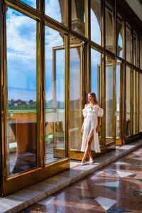 布拉格Grand Hotel International - Czech Leading Hotels的站在窗户上的身着白色衣服的女人