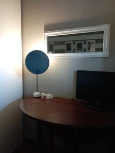 热那亚Amba Alagi Apartment的一张桌子,上面有一台电视和一盏灯