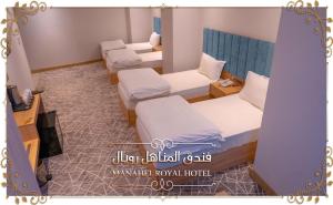 纳杰夫Al-Manahel Royal Hotel的酒店客房设有三张床和壁炉