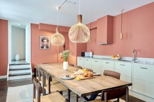 哥本哈根Stylish Spacious Flat w 3BR in Copenhagen City的厨房配有木桌、椅子和粉红色的墙壁