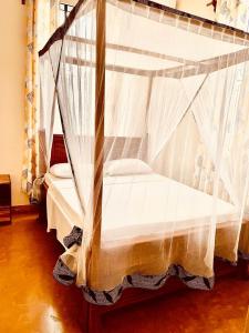 帕杰Mbuyu Uvi Apartment的卧室配有带白色窗帘的天蓬床