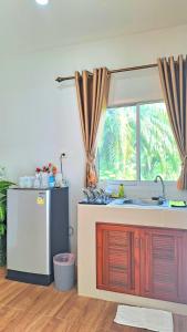 素叻阿曼特拉民宿度假村的厨房设有水槽和窗户。