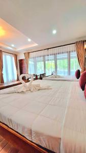 素叻阿曼特拉民宿度假村的窗户客房内的一张大白色床