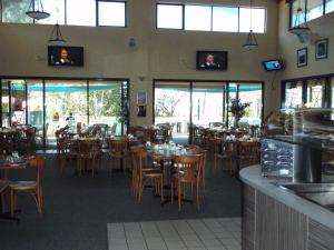 汤斯维尔丛林海滩假日公园的餐厅设有木桌、椅子和窗户。