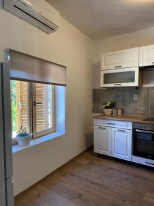 比奥格勒·纳·莫鲁Apartman Kala的厨房配有白色橱柜和窗户。
