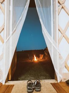 EikažiGlamping Yurt Purvs at Kleja Quiet Camping的火边窗户前的一双鞋