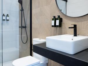 阿斯托加Meraki Suites的一间带水槽、淋浴和镜子的浴室