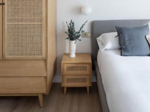 阿斯托加Meraki Suites的一间卧室,卧室配有一张床,床头柜上配有一个花瓶