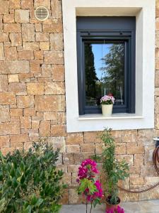 尼基季Kalisti Relax Villa的砖墙上的窗户,两朵盆花