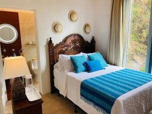 圣卡塔里纳帕洛波Villa Palopo的一间卧室配有一张带蓝色枕头的床和一扇窗户。