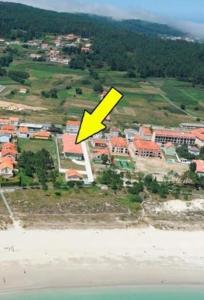 菲尼斯特雷Apartamento cerca de la playa的黄色箭头指向海滩和建筑物