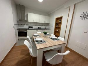 巴利亚多利德Apartamento Lujo centro histórico的厨房配有餐桌和白色椅子