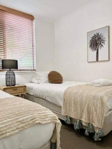 努萨角Paradise plantation on Noosa Hill 143NI的卧室配有两张床,墙上挂着一棵棕榈树