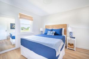 WaterfordMarina Bay Cottages的白色卧室设有蓝色的床和窗户